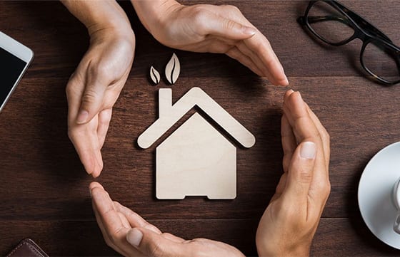 A group of people holding hands around a house.